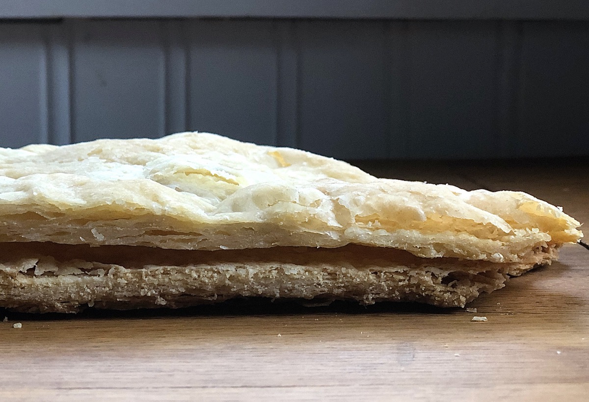 Cross section of two crusts: one made in a stand mixer, one made by hand with chunks of butter 