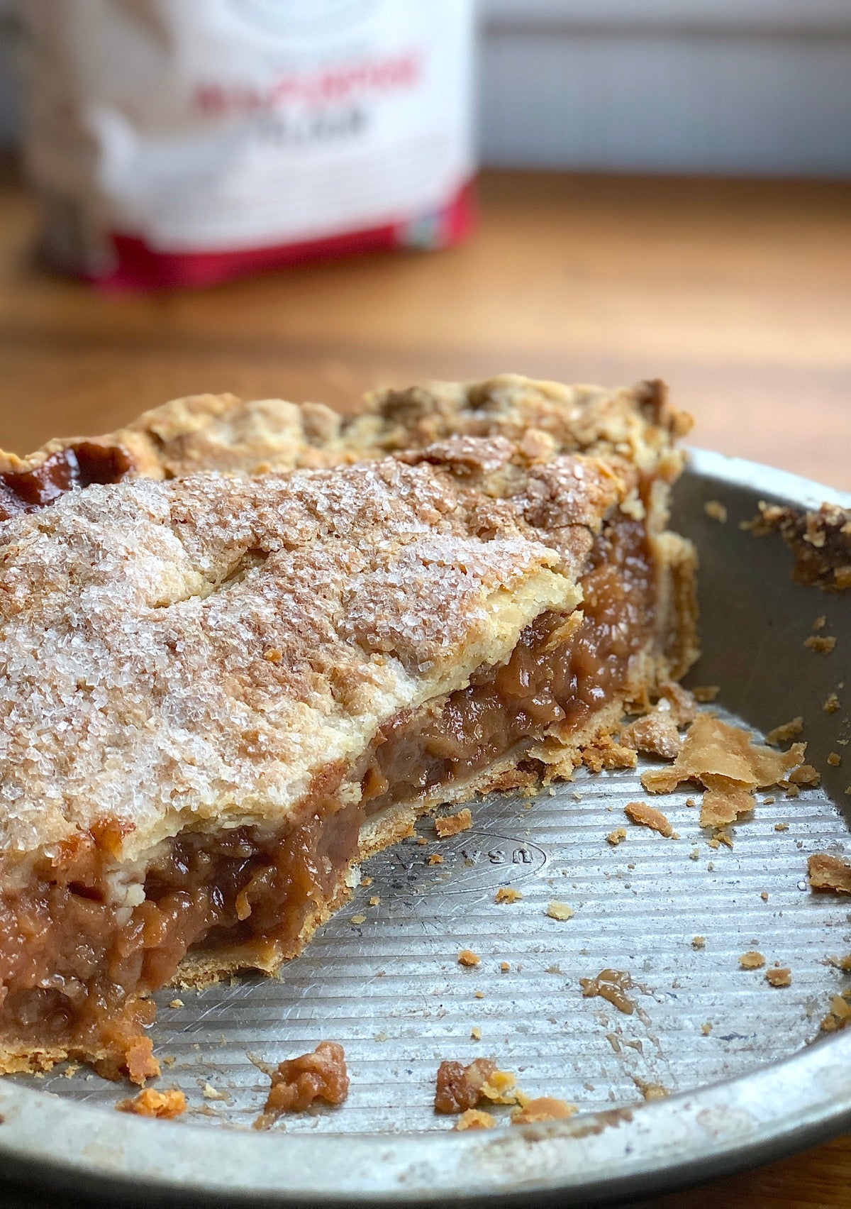 Closeup of half an apple pie in a pie pan, flakes of crust in the bottom of the pan