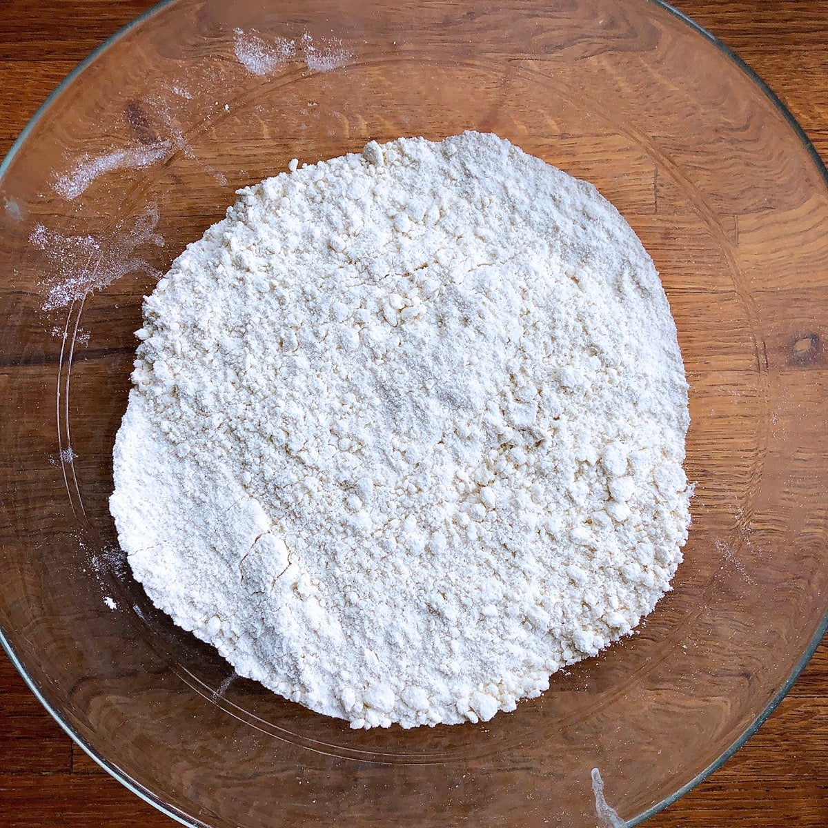 Flour and shortening worked together in a clear, shallow glass bowl.