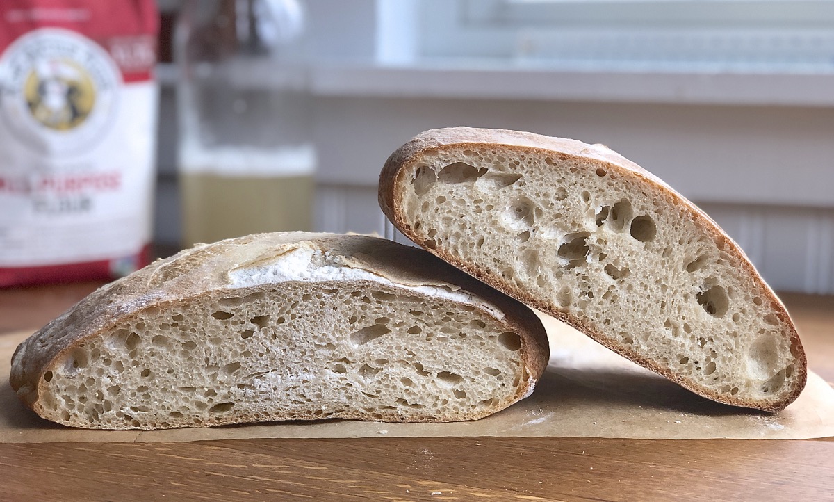 Two loaves of bread — one made with standard starter, one with yeast water —sliced open to show their interior crumb