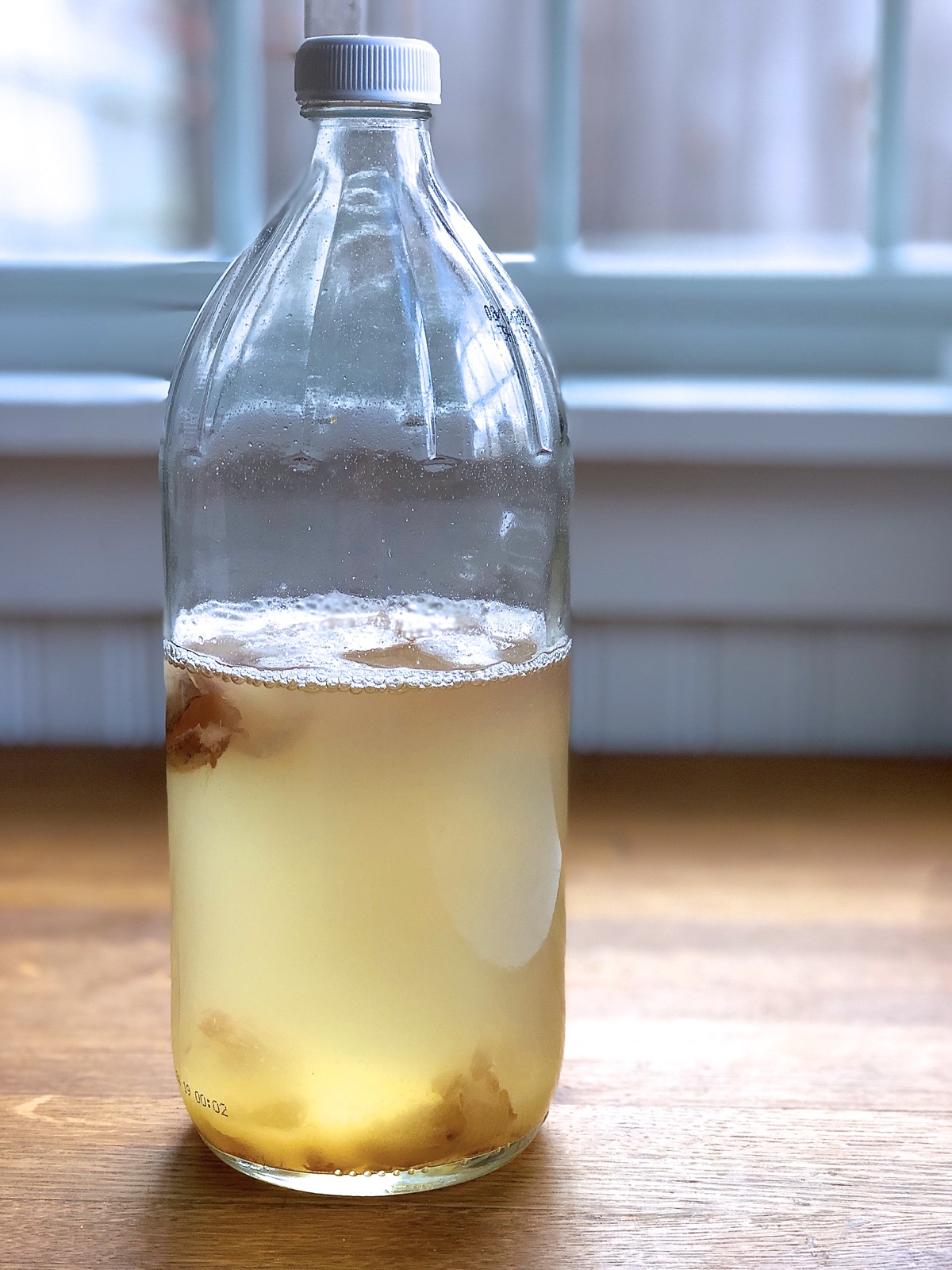 Bottle of yeast water sitting on a wooden table.