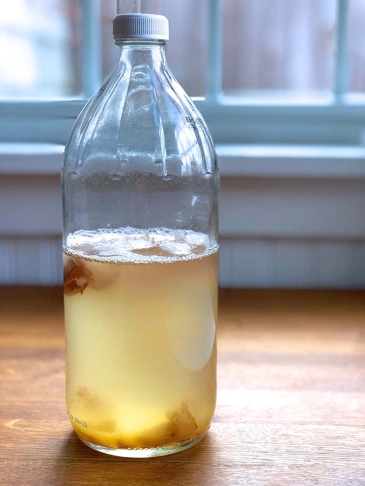 Bottle of yeast water sitting on a wooden table.