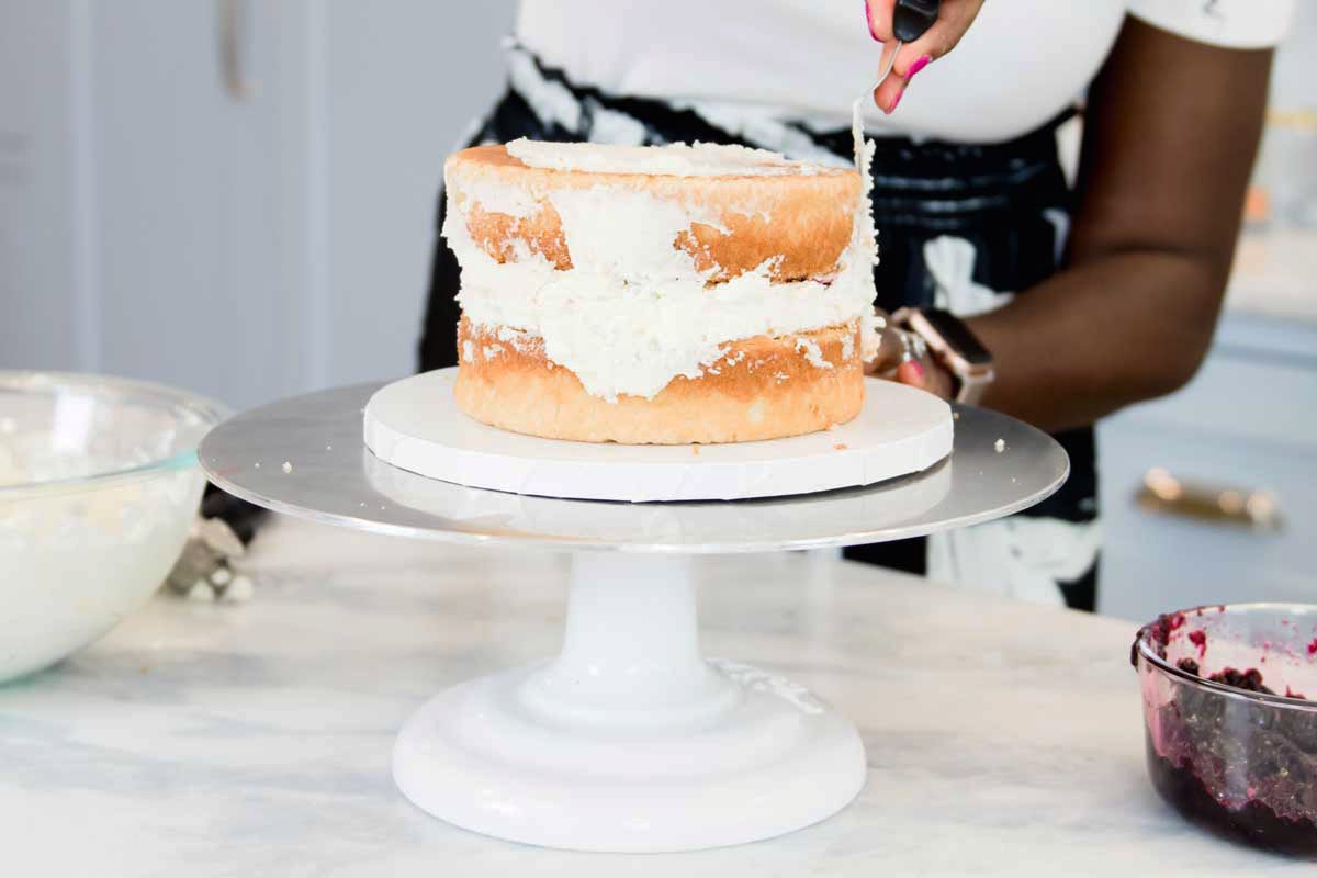 Zainab smoothing frosting onto sides of cake