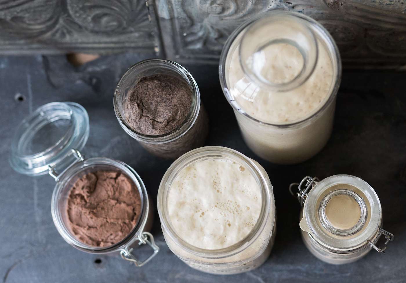 Several ripe preferments in glass jars on a table