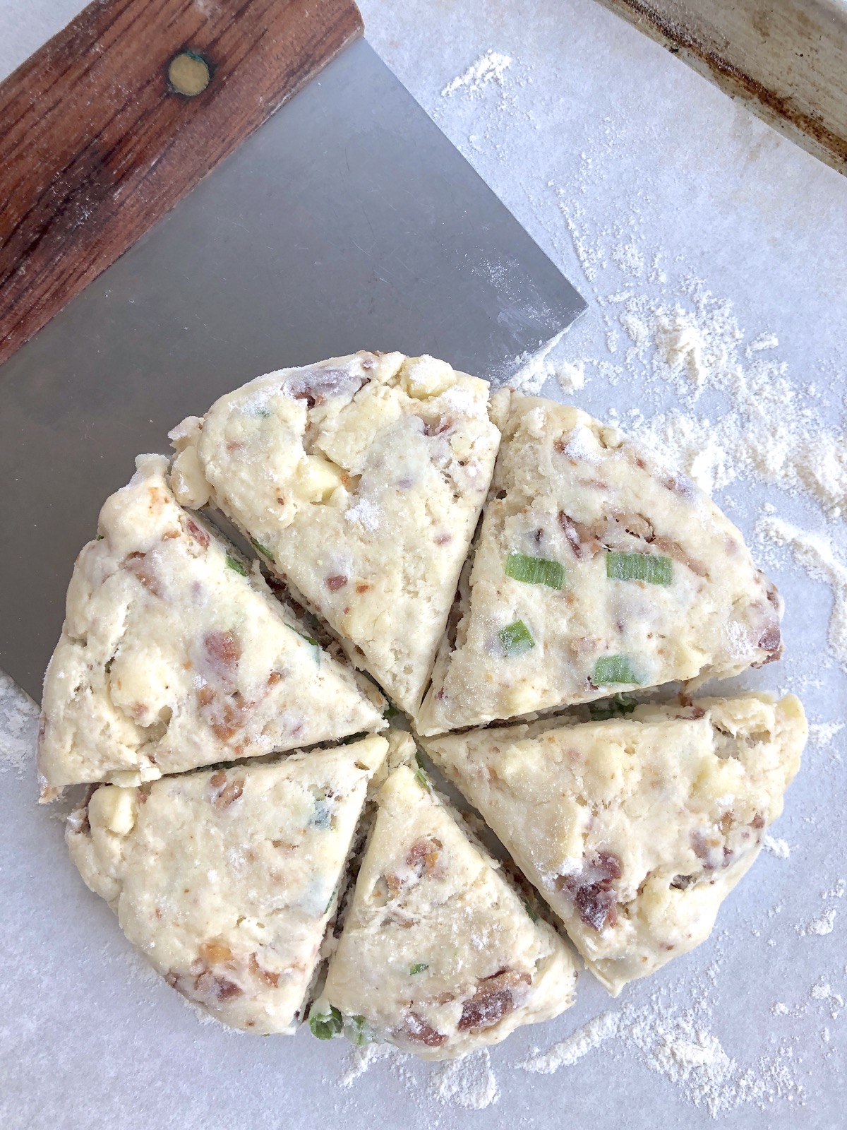 Scone dough patted into a disk and cut into six wedges using a bench knife.