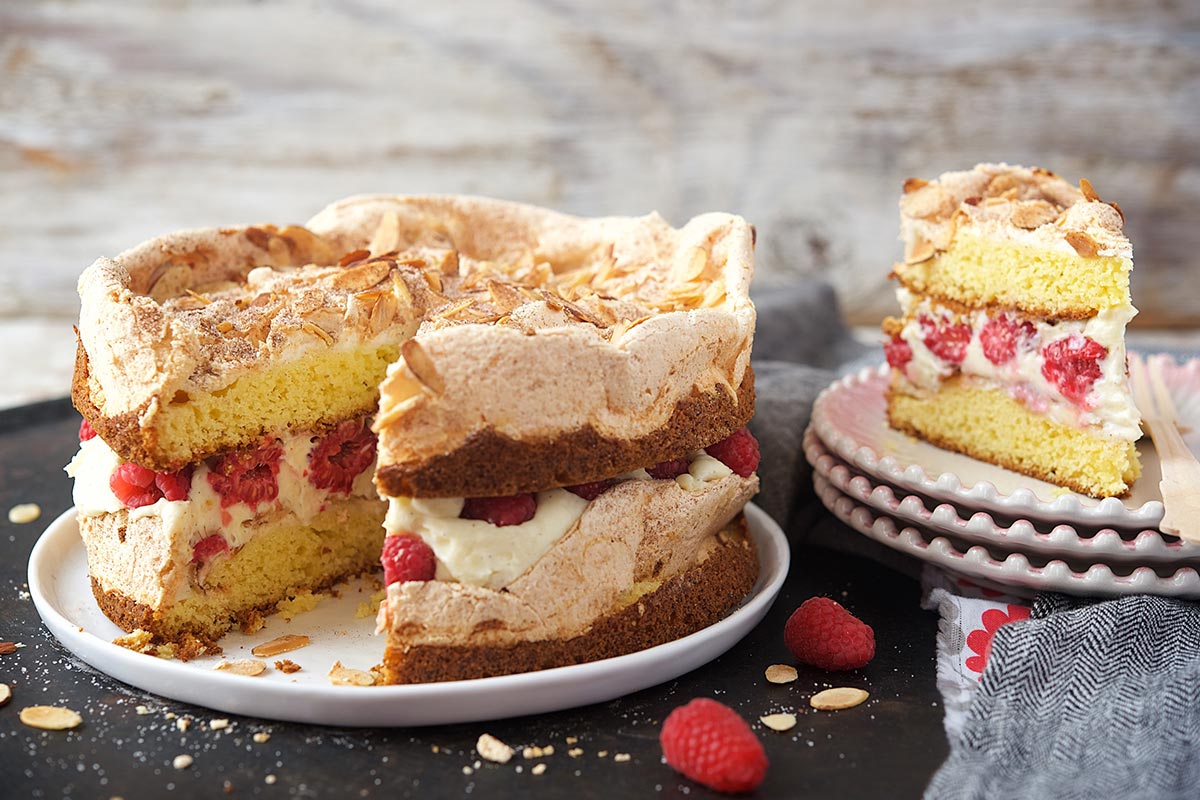 A Blitz Berry Torte with a slice cut out to show pastry cream and berries inside