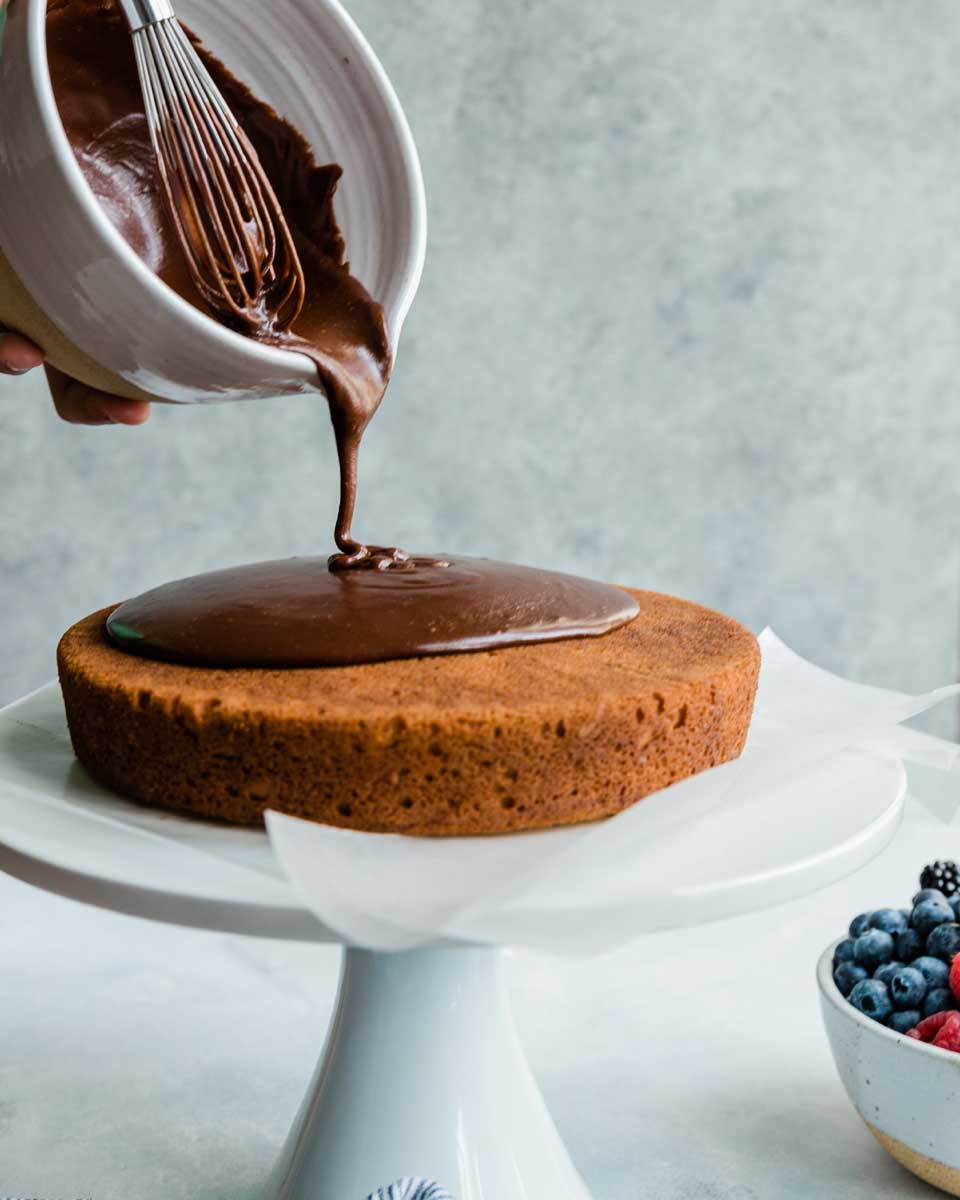 Fudge frosting being poured into cake