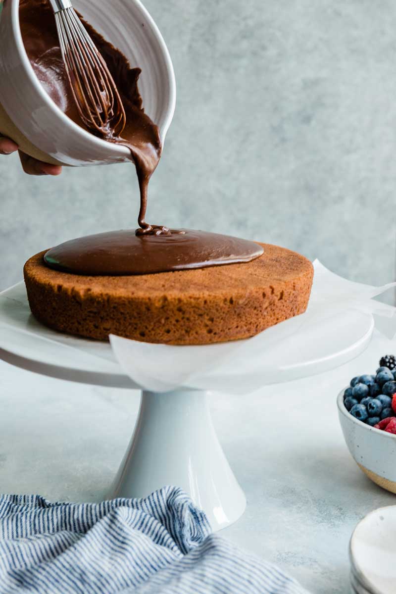 Pouring fudge frosting over cake