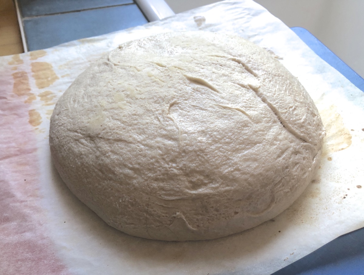 Dough turned out of a bowl onto a floured piece of parchment.