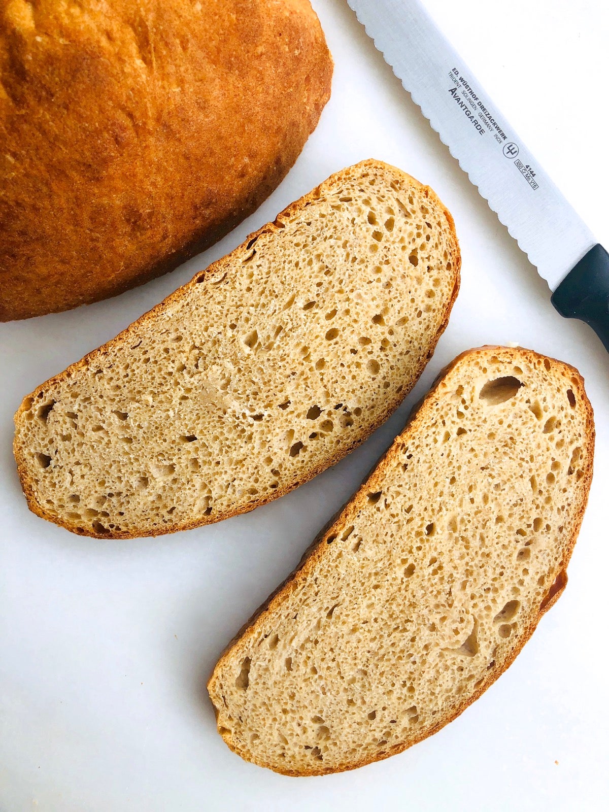 Sliced sourdough bread on a white marble slab.