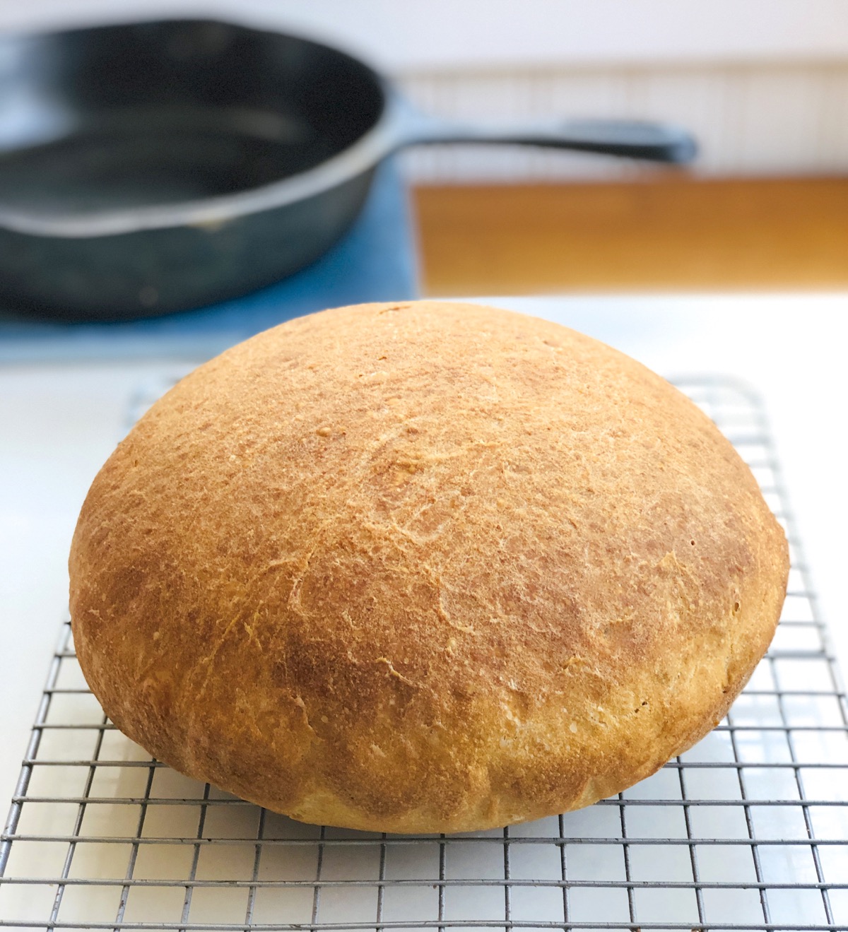 Round, tall loaf of sourdough bread on a cooling rack.