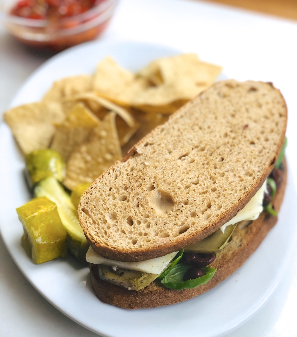 Do-Nothing Sourdough Bread made into a sandwich, on a plate with chips and pickles. 