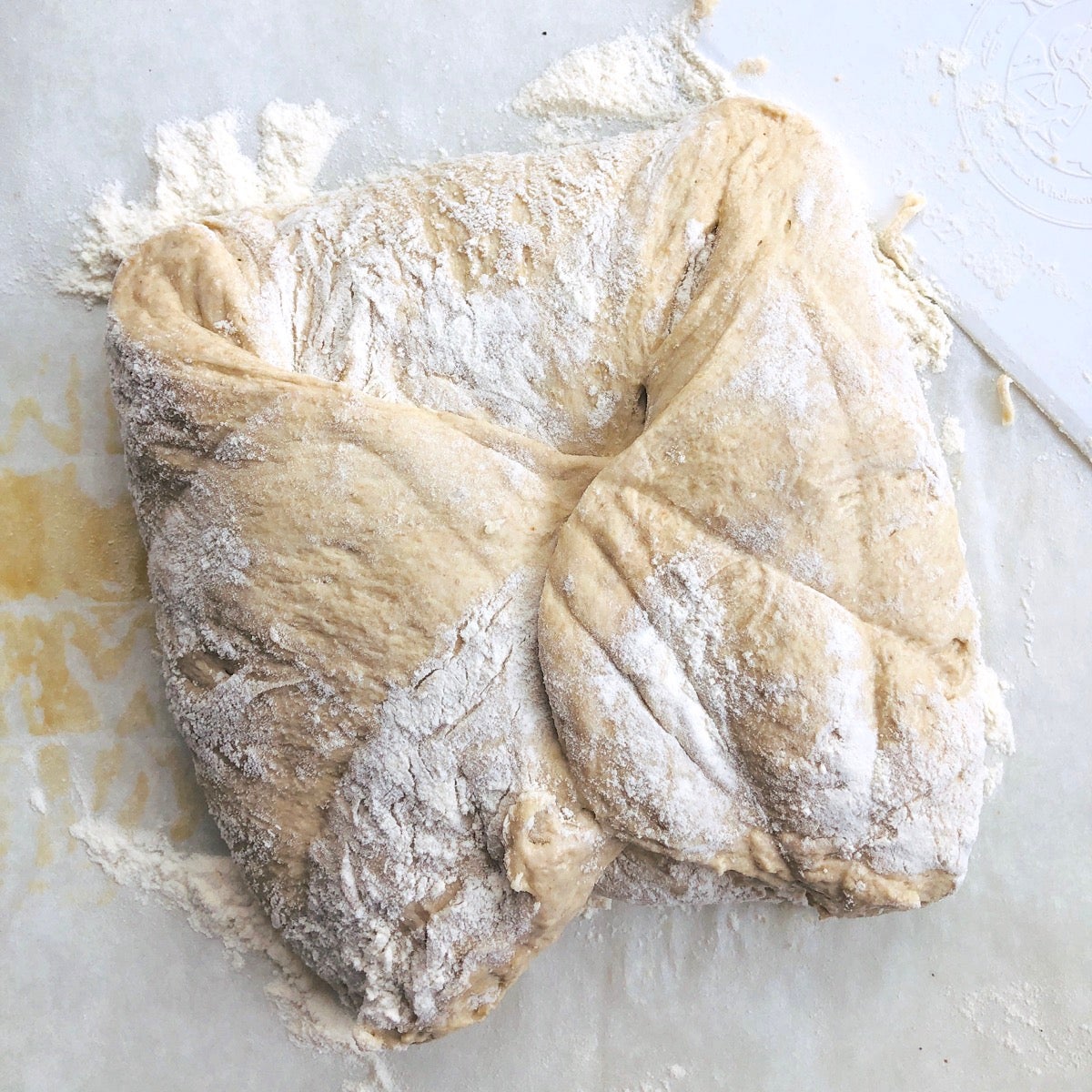 Sticky dough on a floured work surface, the four edges folded into the center.