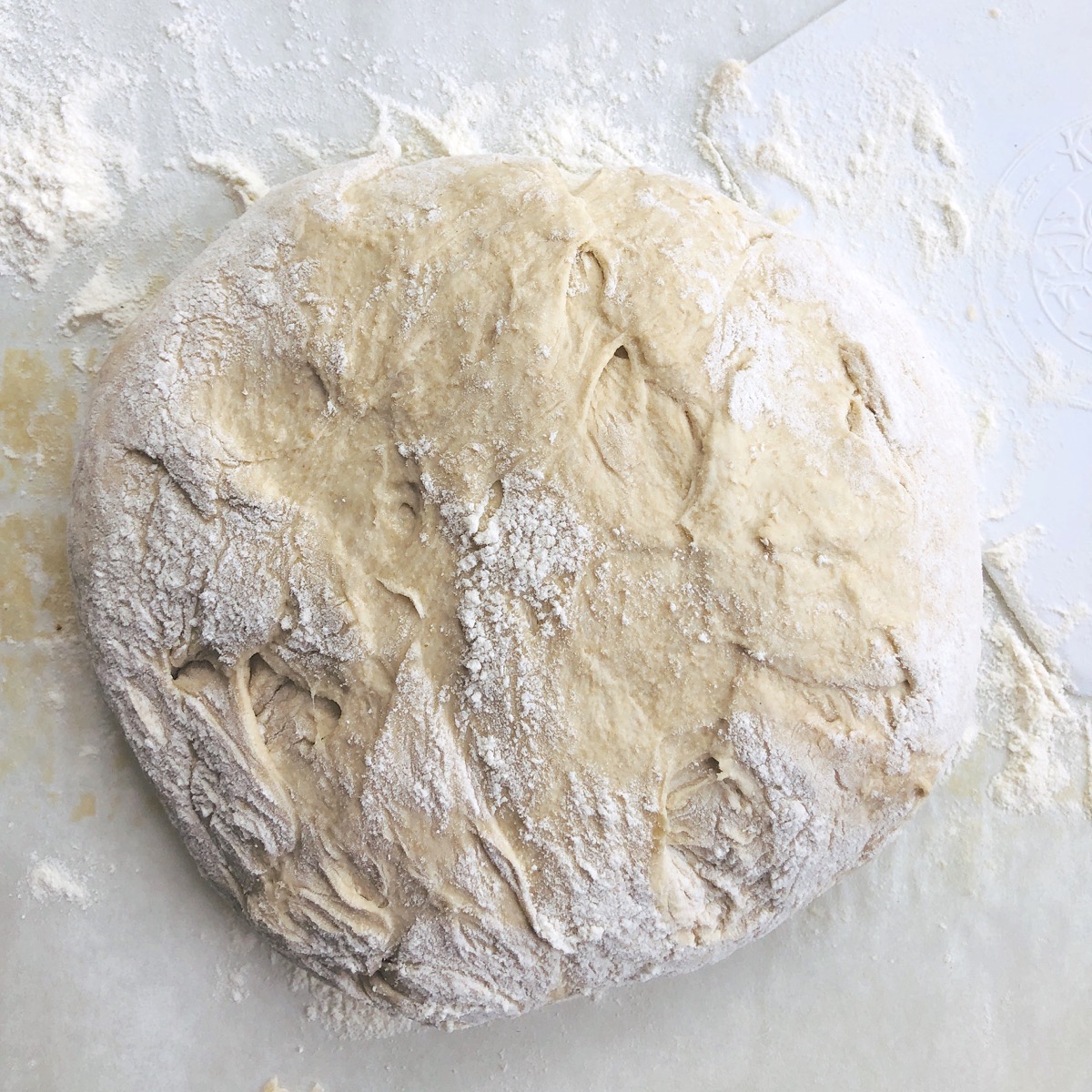 Sticky dough formed into a round ball on a floured work surface.