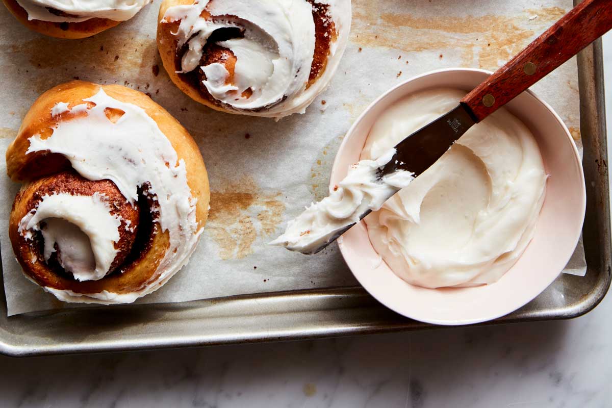 Bowl of icing next to rolls