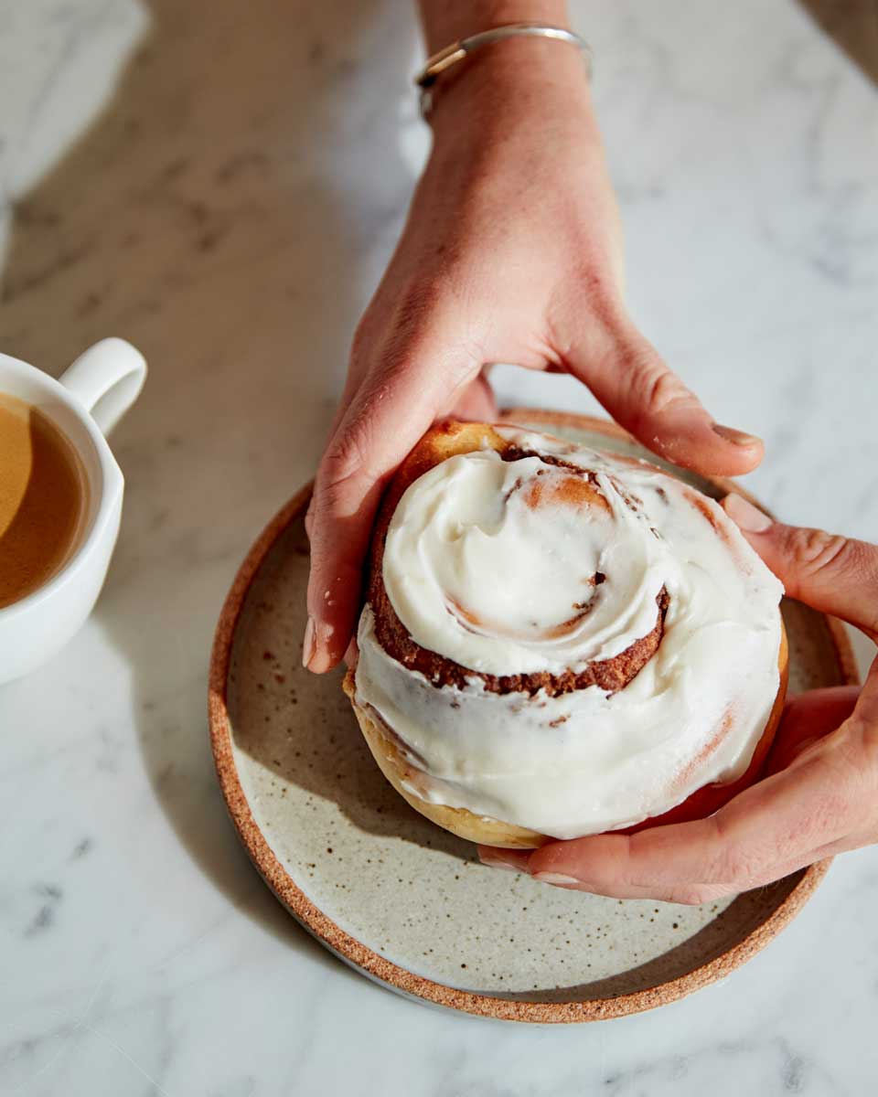 Hands holding a cinnamon roll 