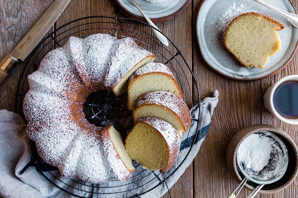 A gluten-free vanilla Bundt cake cut into slices and dusted with confectioners' sugar