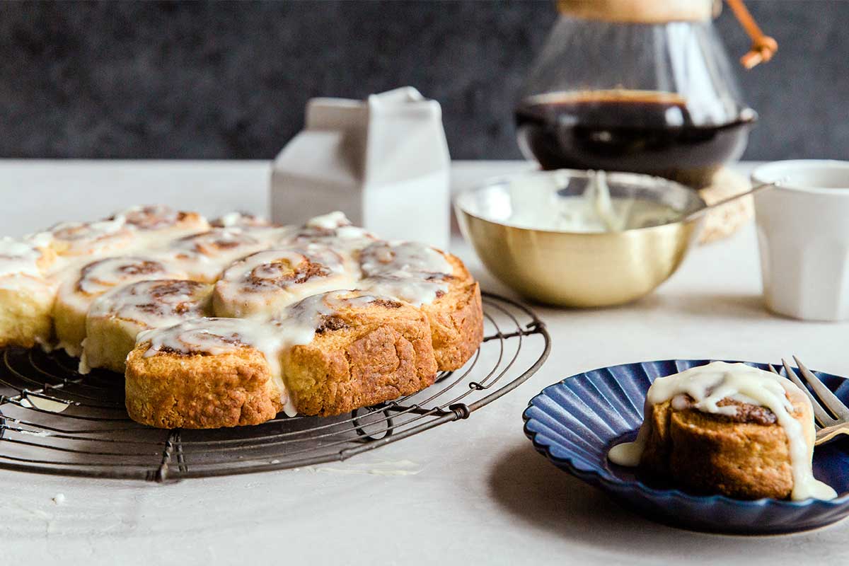 A plate of Instant Graitification Cinnamon Rolls (made with baking powder rather than yeast) next to a carafe of coffee