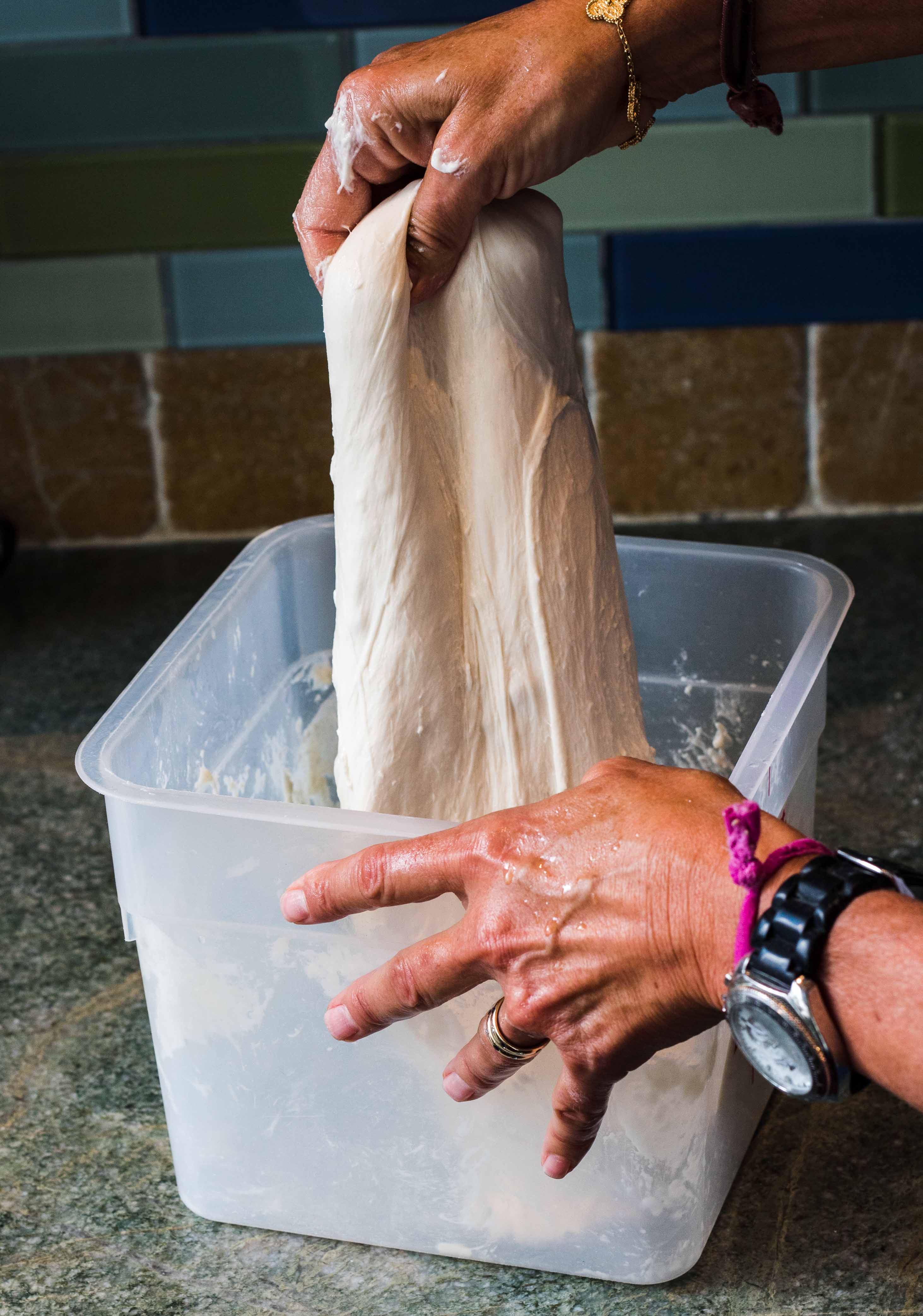 Pulling wet dough out of container to fold it
