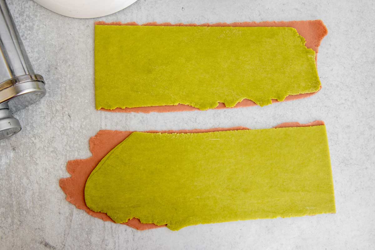 Green sheet of dough stacked over pink sheet of dough