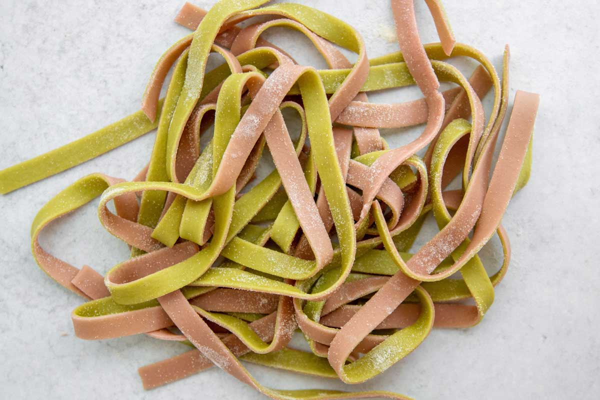 Two-toned green and pink pasta cut into strips
