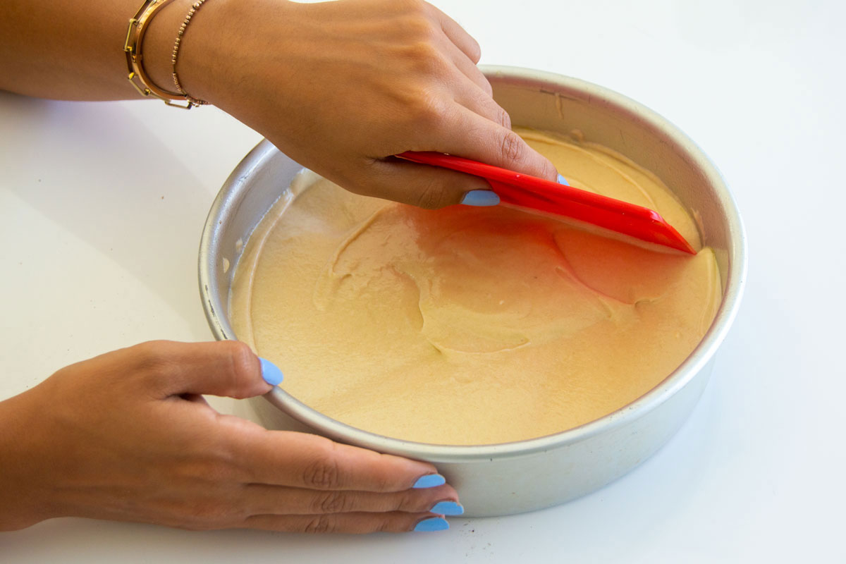 Smoothing cake batter in pan with dough scraper