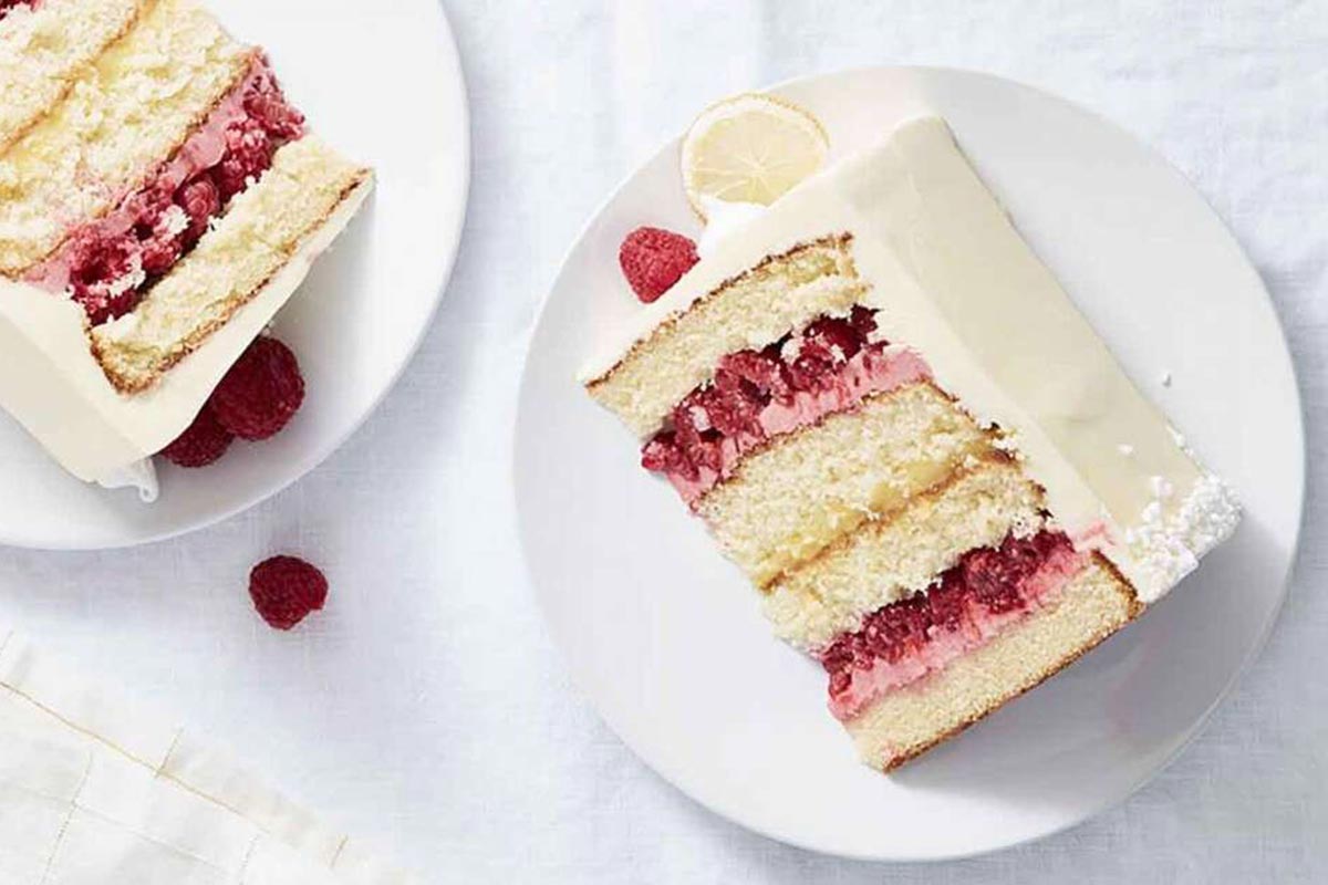 A slice of Lemon Raspberry Cake on a plate, showing off layers of lemon curd, raspberry filling, and sponge cake