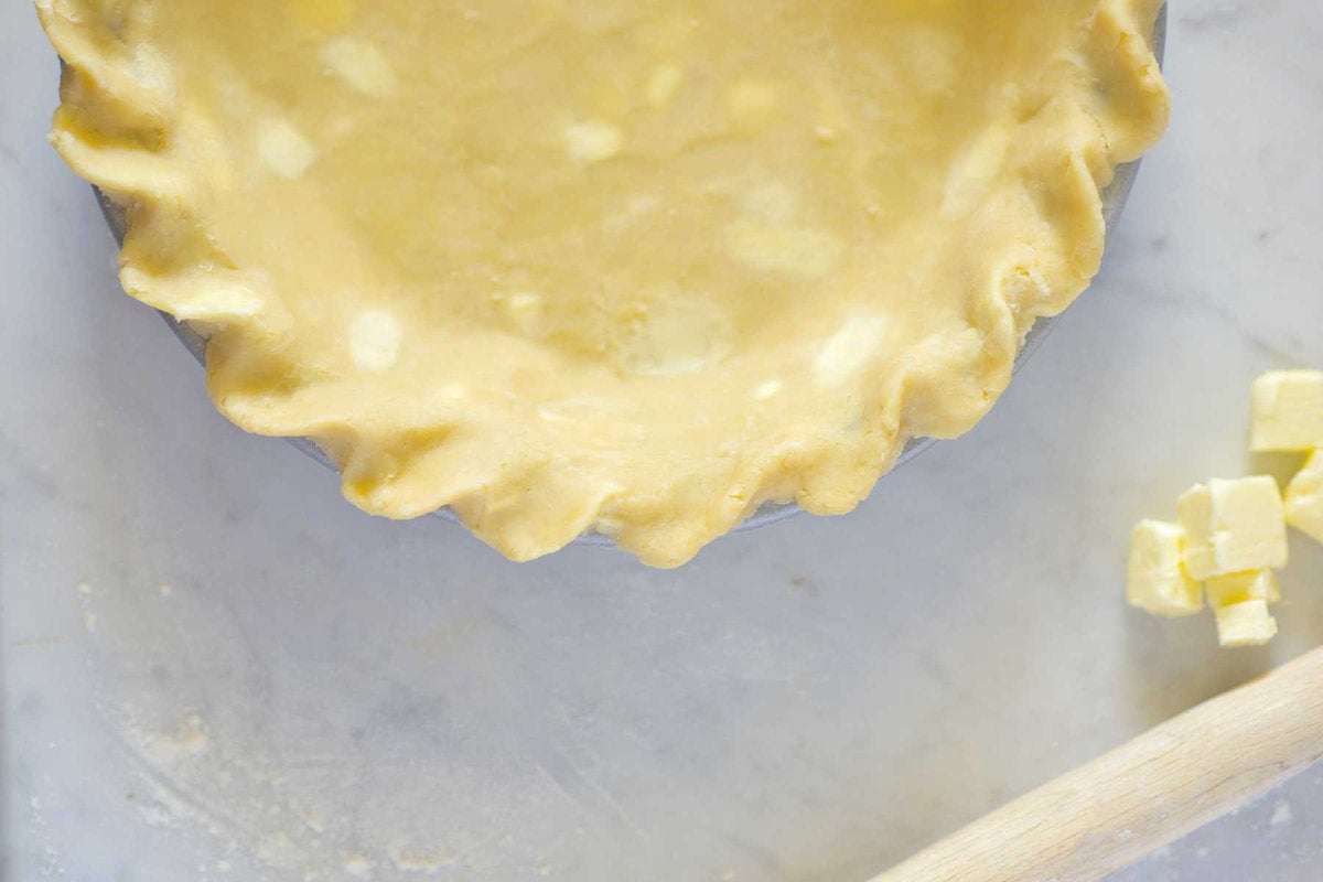 Unbaked pie crust in the plate, with butter chunks visible