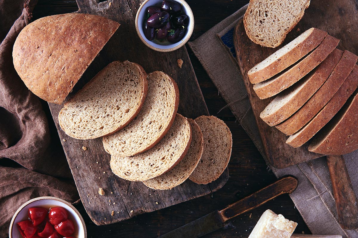 A loaf of Russian Rye Bread cut into slices on a wooden cutting board