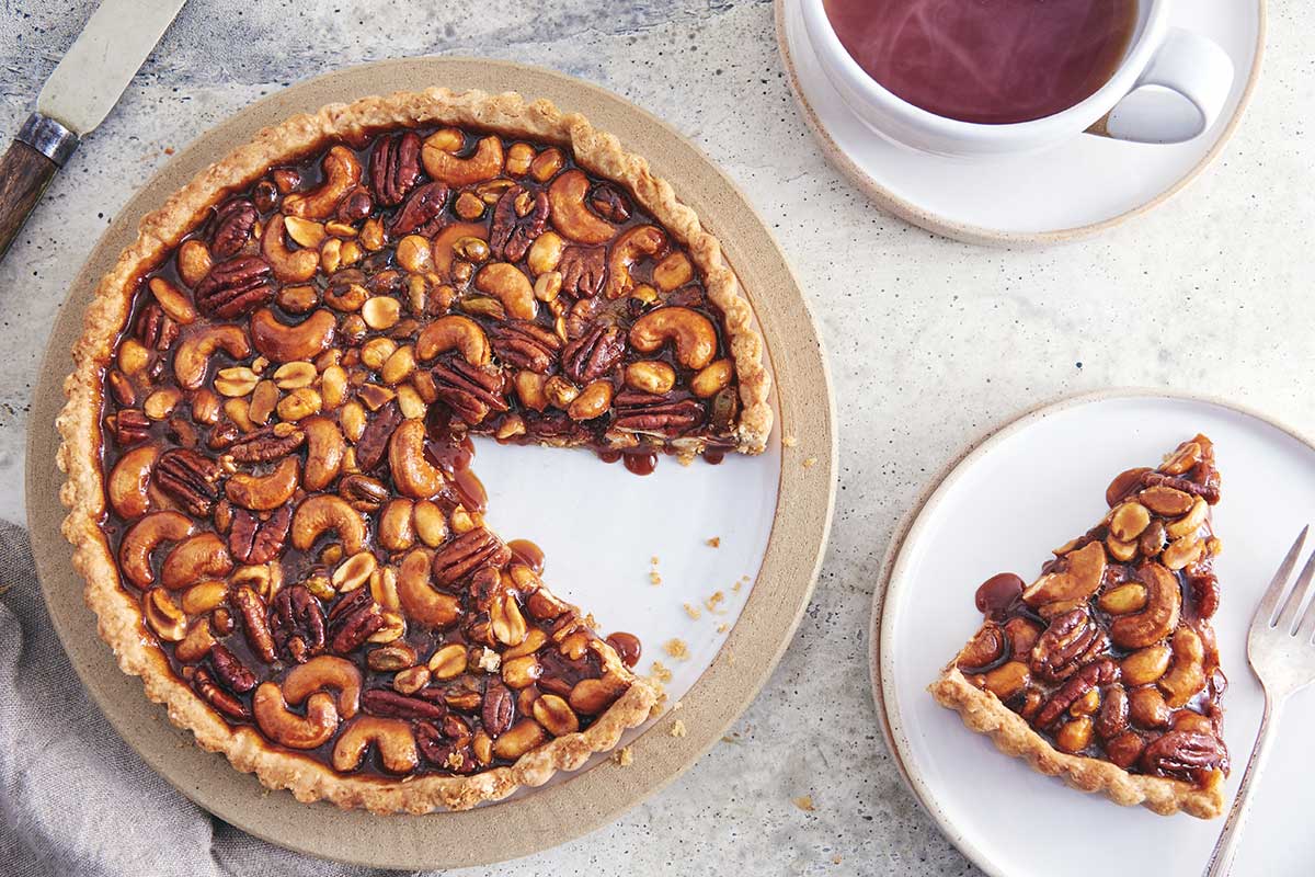 Salted caramel nut tart with rye crust in the pan, with a plated slice next to it