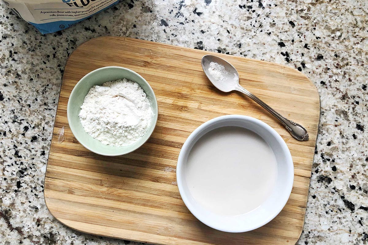 Bowl of almond milk next to bowl of flour