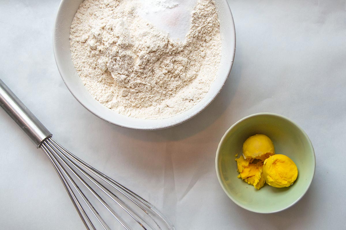 Dry ingredients next to bowl of boiled egg yolks