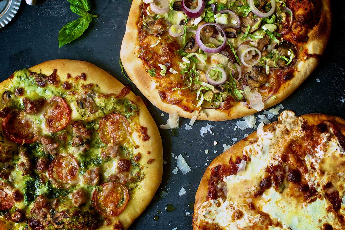 Three homemade pizzas on a kitchen table