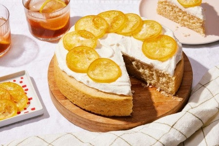 A simple, single layer lemon cake topped with frosting and candied lemon slices