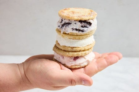 Three sandwich bread ice cream sandwiches stacked on top of each other in a baker's hand