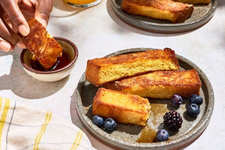 Dipping a French Toast Stick into a small dish of maple syrup.