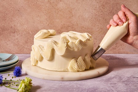 frosting being piped on a frosted cake