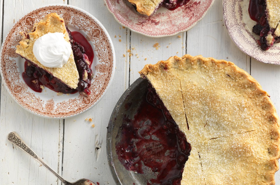 A cherry pie made with a gluten-free crust with a few slices on plates, ready to be enjoyed