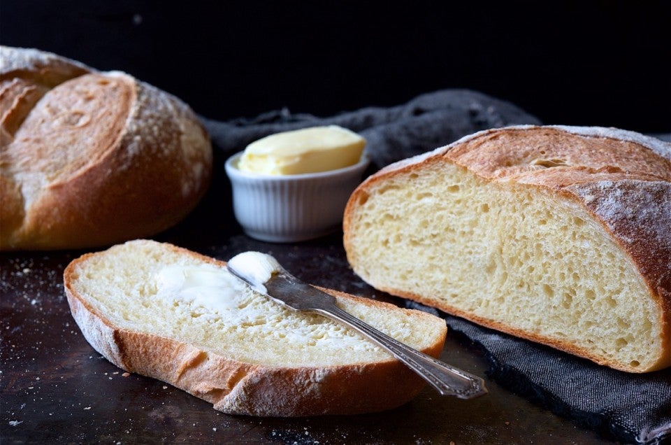 Loaves of sourdough bread on a cutting board, one loaf sliced.