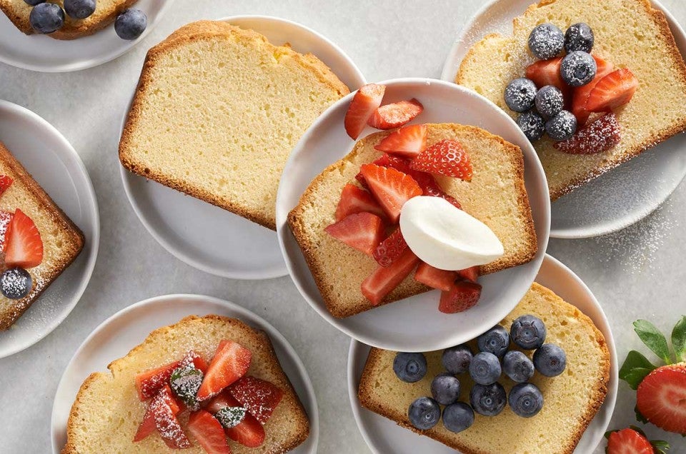 Slices of pound cake on plates topped with fresh fruit and berries