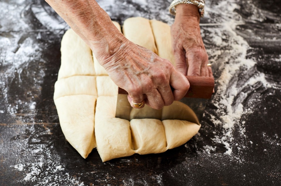 Hands cutting dough into rolls