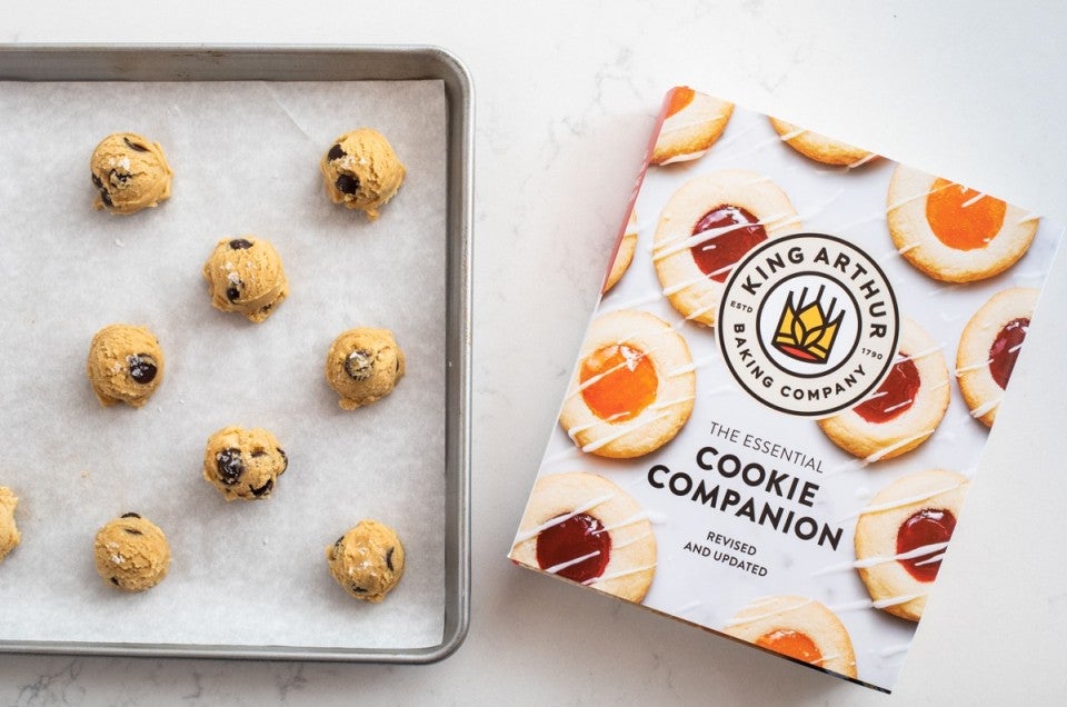 The Essential Cookie Companion book and unbaked drop cookies on a baking sheet.