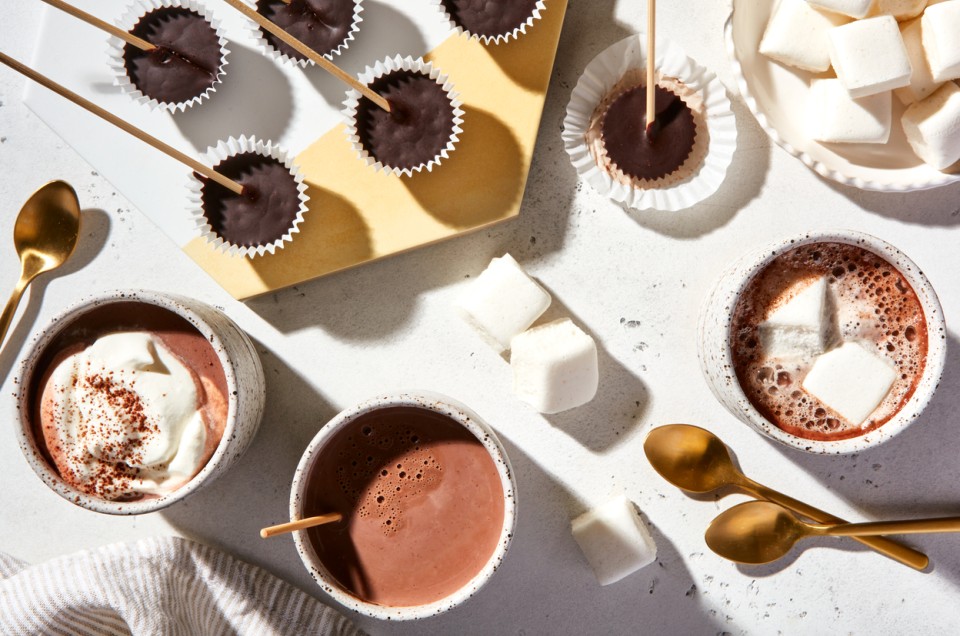 Mugs of keto hot chocolate alongside various toppings