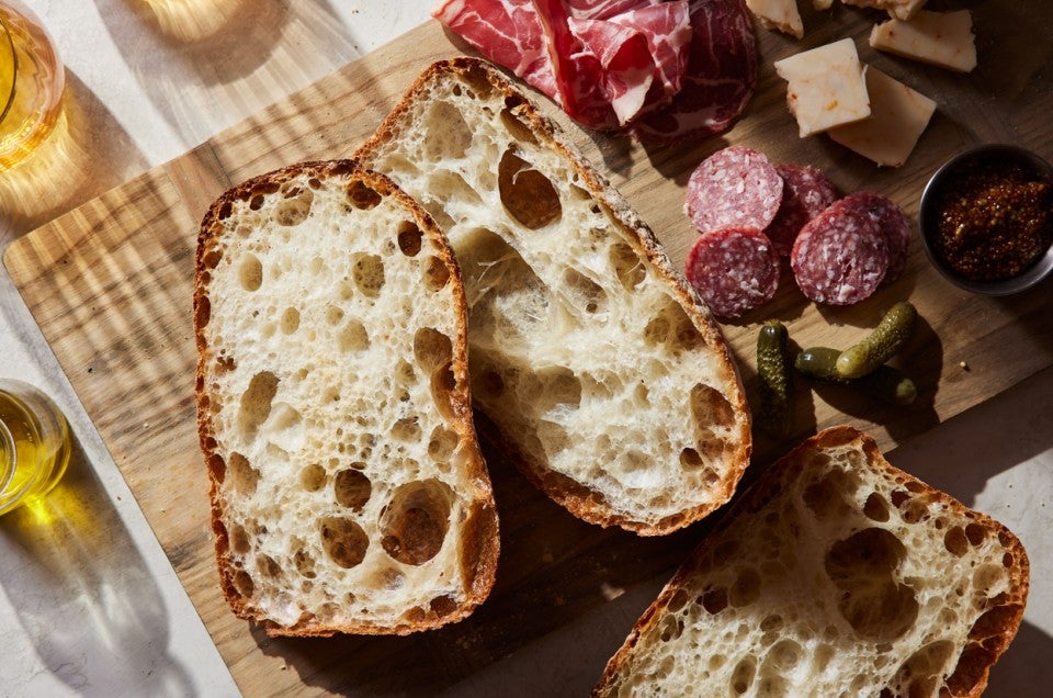 Sliced Pan de Cristal loaves on a cheese board - select to zoom