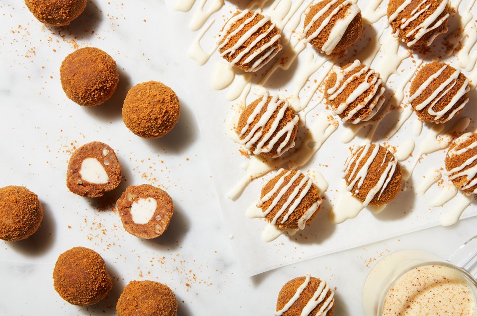 Eggnog truffles drizzles with glaze, some broken in half to reveal a creamy center - select to zoom
