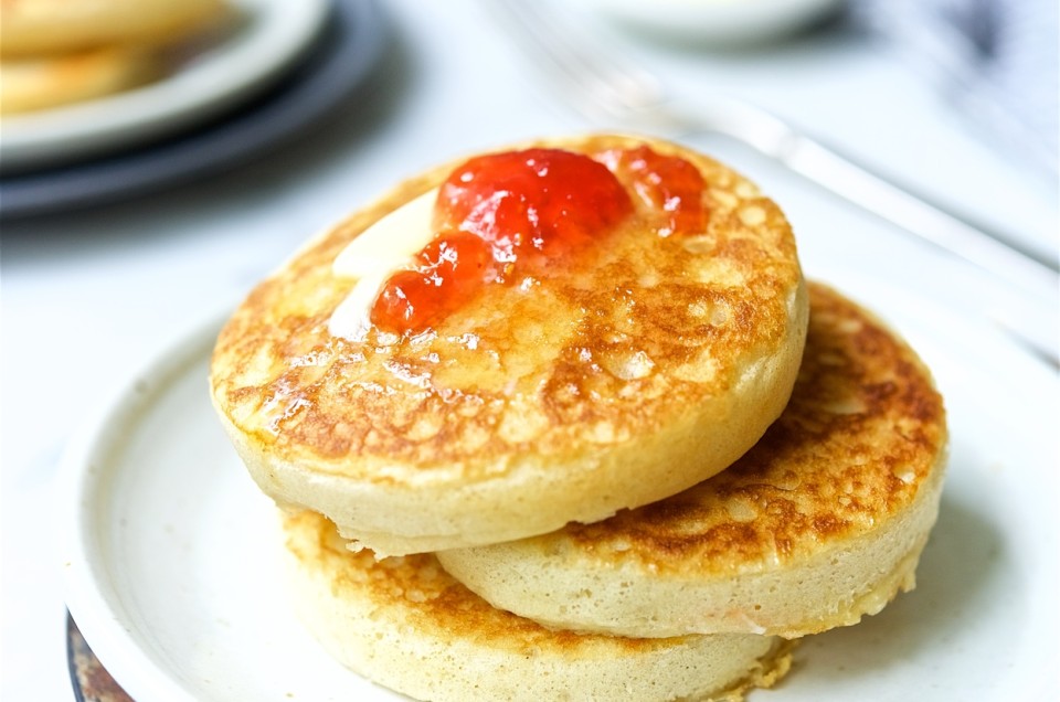 A stack of sourdough crumpets topped with butter and jam - select to zoom