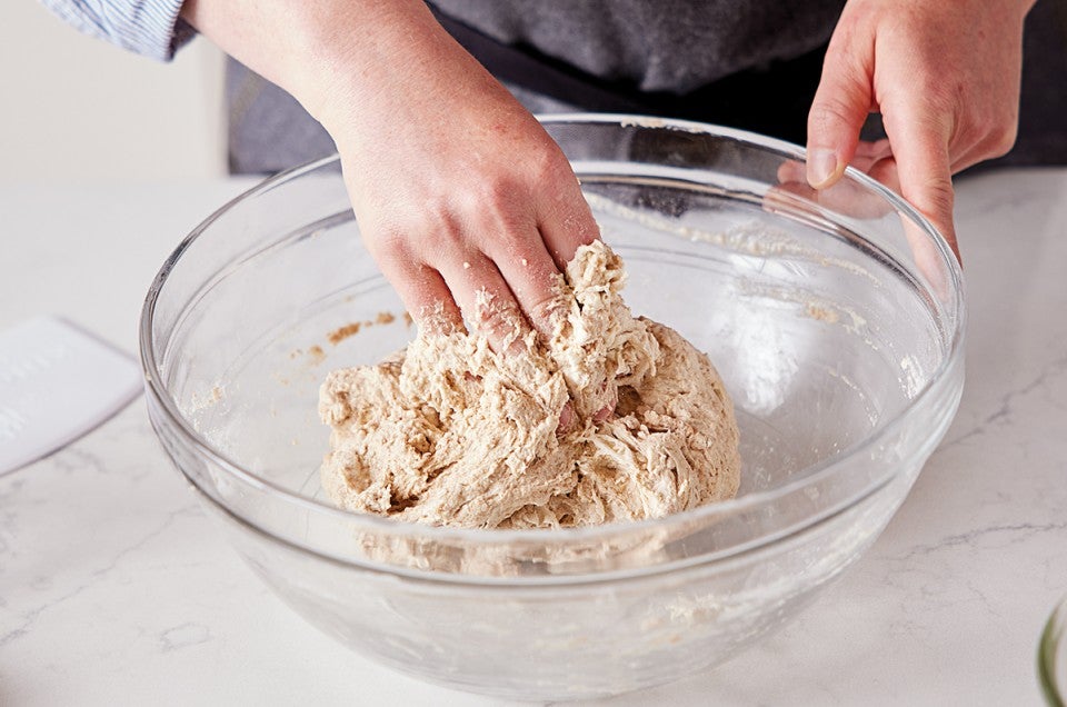 Hands covered in sticky bread dough while kneading