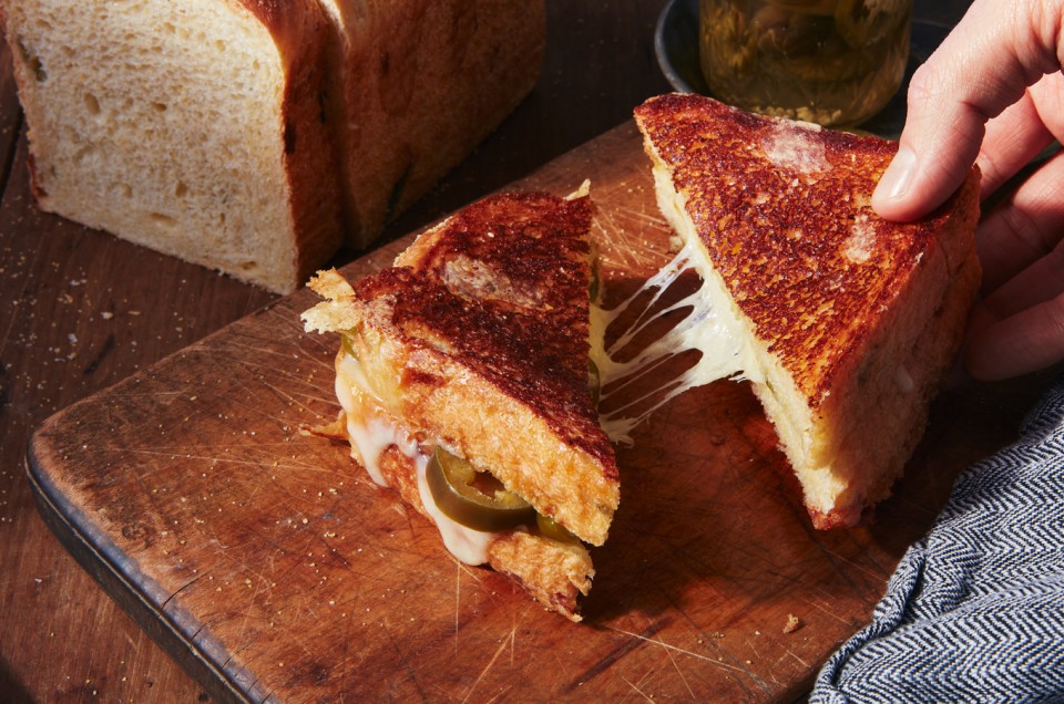 Hand pulling a triangle of a grilled cheese sandwich with cheese pull