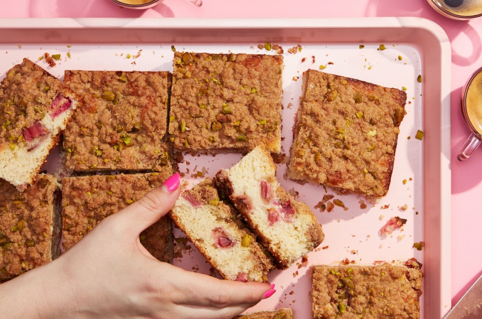 Hands holding square slices of rhubarb-ginger buckle cake