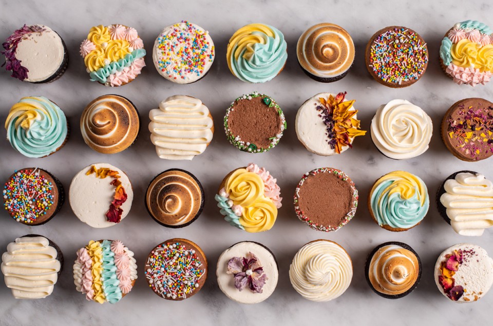 A grid of cupcakes decorated with all different techniques